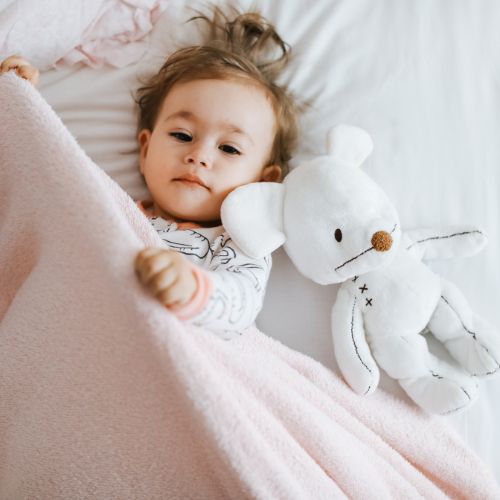 bebe-fille-dans-son-lit-avec-une-couverture-et-son-doudou